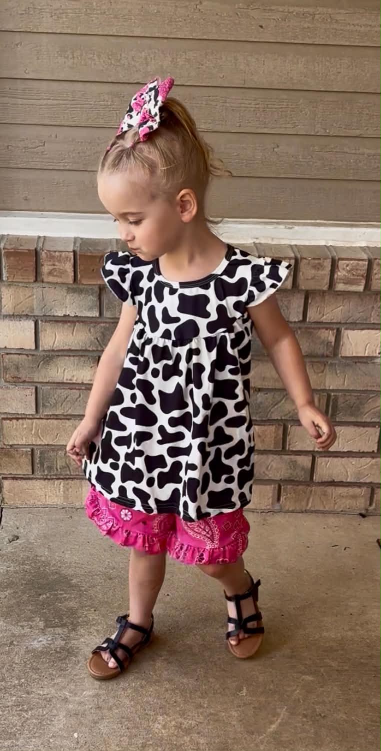 young girl wearing pink paisley print shorts and a cowprint top 