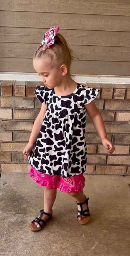 young girl wearing pink paisley print shorts and a cowprint top 